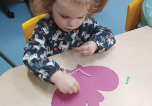 dziewczynka przykleja ozdoby do rękawiczki