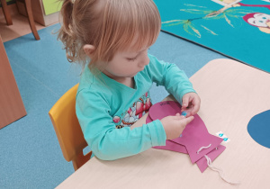 dziewczynka przykleja ozdoby do rękawiczki