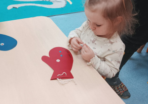 dziewczynka przykleja ozdoby do rękawiczki