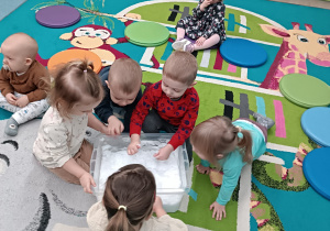 dzieci dotykają śniegu w pojemniku