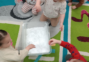 dzieci wkładają ręce do pojemnika ze śniegiem