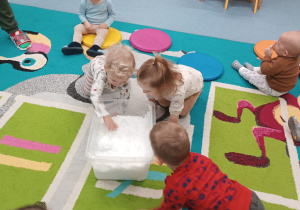 dzieci wkładają rączki do pojemnika ze śniegiem