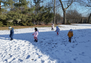 dzieci stoją i spacerują po śniegu