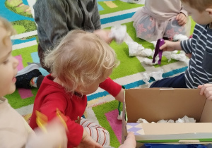 dzieci próbują łapać kulki papierowe za pomocą pęset