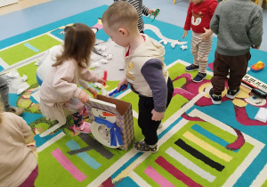 dzieci wkładają za pomocą pęset papierowe kulki do pudełka