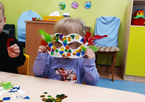 dziewczynka pokazuje zrobioną przez siebie maskę