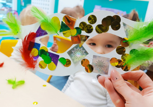 dziecko spogląda przez zrobioną przez siebie maskę