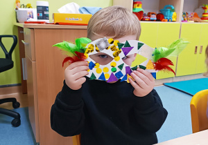 chłopiec patrzy przez udekorowaną przez siebie maskę