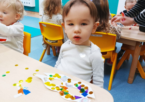 chłopiec siedzi przy stoliku przed nim leży maska