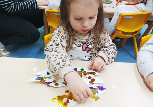 dziewczynka przykleja ozdoby na maskę