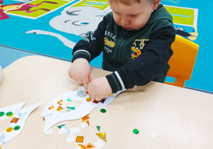 chłopiec przykleja ozdoby na swoją maskę