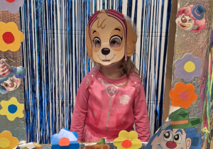 dziewczynka przebrana z maską na twarzy pozuje do zdjęcia w fotobudce