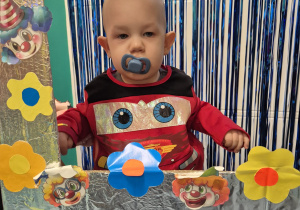 chłopiec ze smoczkiem w buzi pozuje w fotobudce do zdjęcia