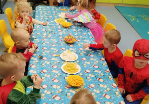 dzieci siedzą przy stoliku, na którym stoją przekąski