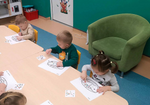 dzieci siedzą przy stoliku i wykonują pracę plastyczną