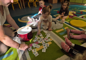 dziewczynka wybiera obrazki spośród rozsypanych na dywanie