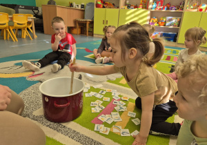 dziewczynka miesza w garnku łyżką drewnianą