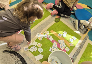 dziewczynka wybiera obrazki spośród tych rozsypanych na podłodze