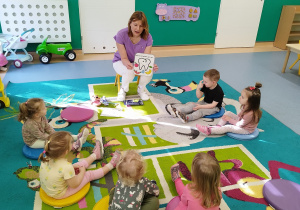 opiekunka pokazuje dzieciom ilustrację wesołego ząbka i tego co mu pomaga być zdrowym