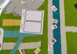 na dywanie leży kartka z tabelką dla zadowolonego ząbka i smutnego ząbka, a wokół obrazki, które należy im przyporządkować