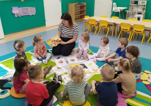 wszyscy siedzą na dywanie i słuchają czytanego przez opiekunkę opowiadania