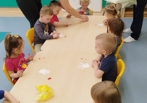 opiekunki pomagają dzieciom wykonać pracę plastyczną