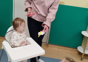 opiekunka pokazuje dziewczynce wykonaną kurkę, dziewczynka uśmiecha się