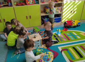 dzieci siedzą na dywanie, bawią się zabawkami