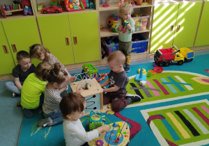 dzieci na dywanie bawią się stolikami edukacyjnymi