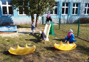 dziewczynka wchodzi na zjeżdżalnię, inna się buja na bujaku