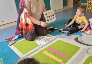 opiekunka pokazuje dzieciom zdjęcia motyli