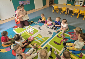 wszyscy siedzą na dywanie i słuchają opowiadania opiekunki