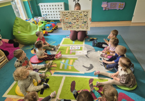 opiekunka pokazuje dzieciom dużą planszę z różnymi motylami
