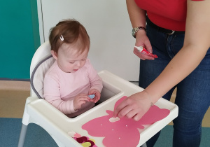 opiekunka pomaga dziewczynce wyklejać