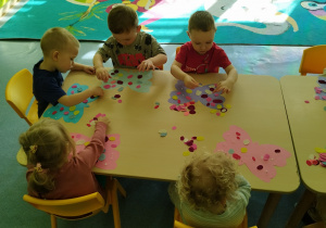 dzieci przy stoliku ozdabiają motyle