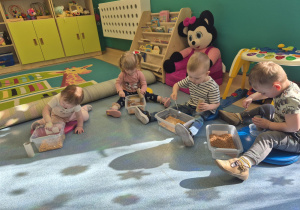 dzieci siedzą i bwaią się tym, co mają w pudełku