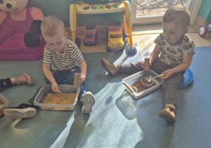 dzieci bawią się tym, co mają w pudełku przed sobą