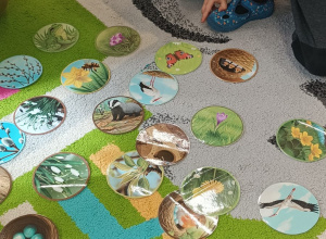 na dywanie leżą obrazki , dzieci siedzą wokół