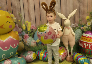 chłopiec z opaską uszy królika na głowie, trzyma balona-pisankę