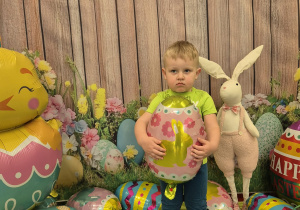 chłopiec stoi i patrzy, trzyma balona pisankę