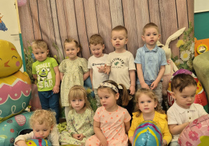dzieci wspólnie pozują do zdjęcia, niektóre siedzą i trzymają pisanki balony, inne stoją