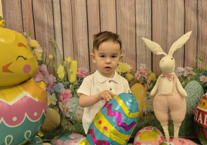 chłopiec stoi i trzyma balona pisankę