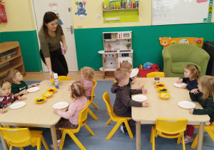 dzieci siedzą przy stolikach, przed nimi leżą gofry i dodatki