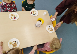 opiekunka pomaga ozdabiać dzieciom gofry