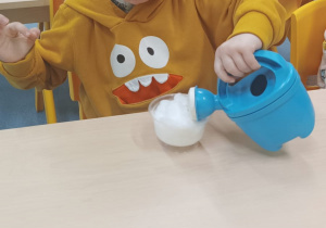 chłopiec podlewa konewką rzeżuchę