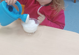 dziewczynka podlewa konewką rzeżuchę