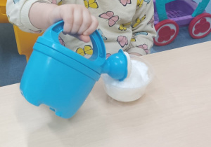 dziewczynka podlewa konewką rzeżuchę