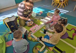 opiekunka pokazuje dzieciom co znajduje się w koszyczku