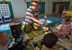 opiekunka pokazuje dzieciom zdjęcia wielkanocnych palemek