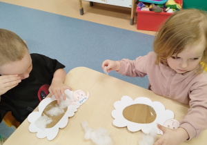 chłopiec wykleja baranka watą, a dziewczynka patrzy